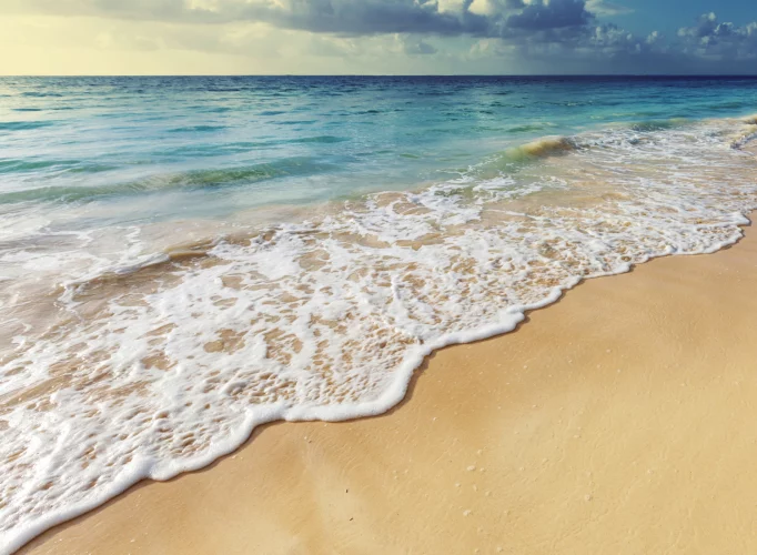 A clear blue sky above gentle waves rolling onto a serene beach, evoking calm and tranquility, key elements in the therapeutic environment provided by Andreia Fortes Counselling.